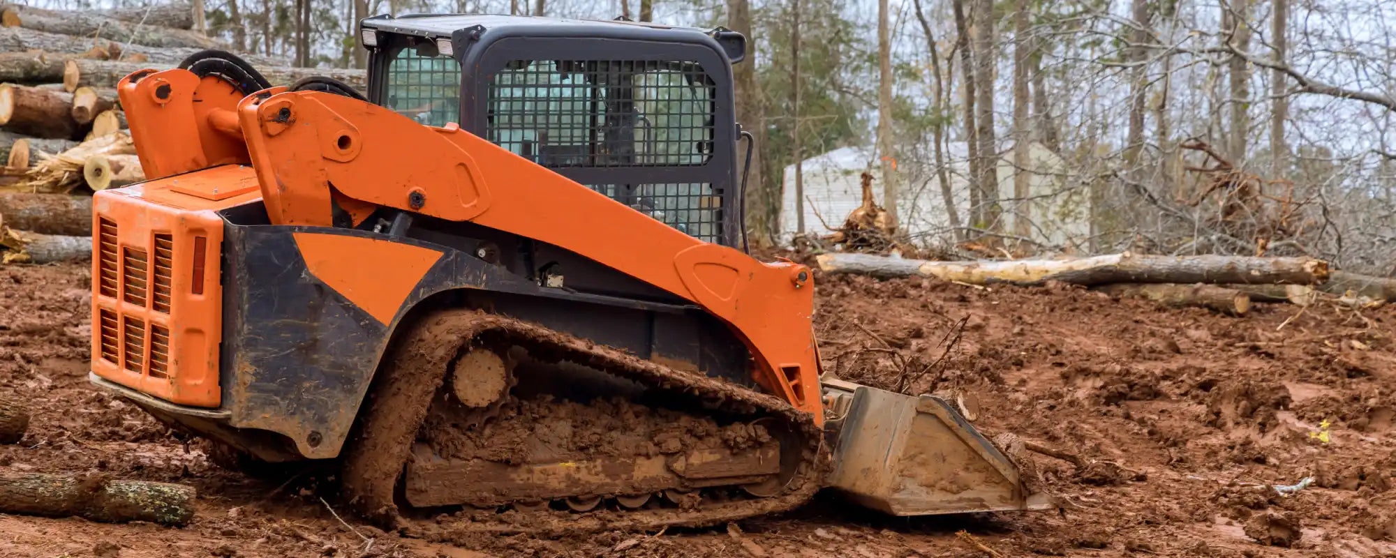 Orange and black compact track loader with a front bucket.