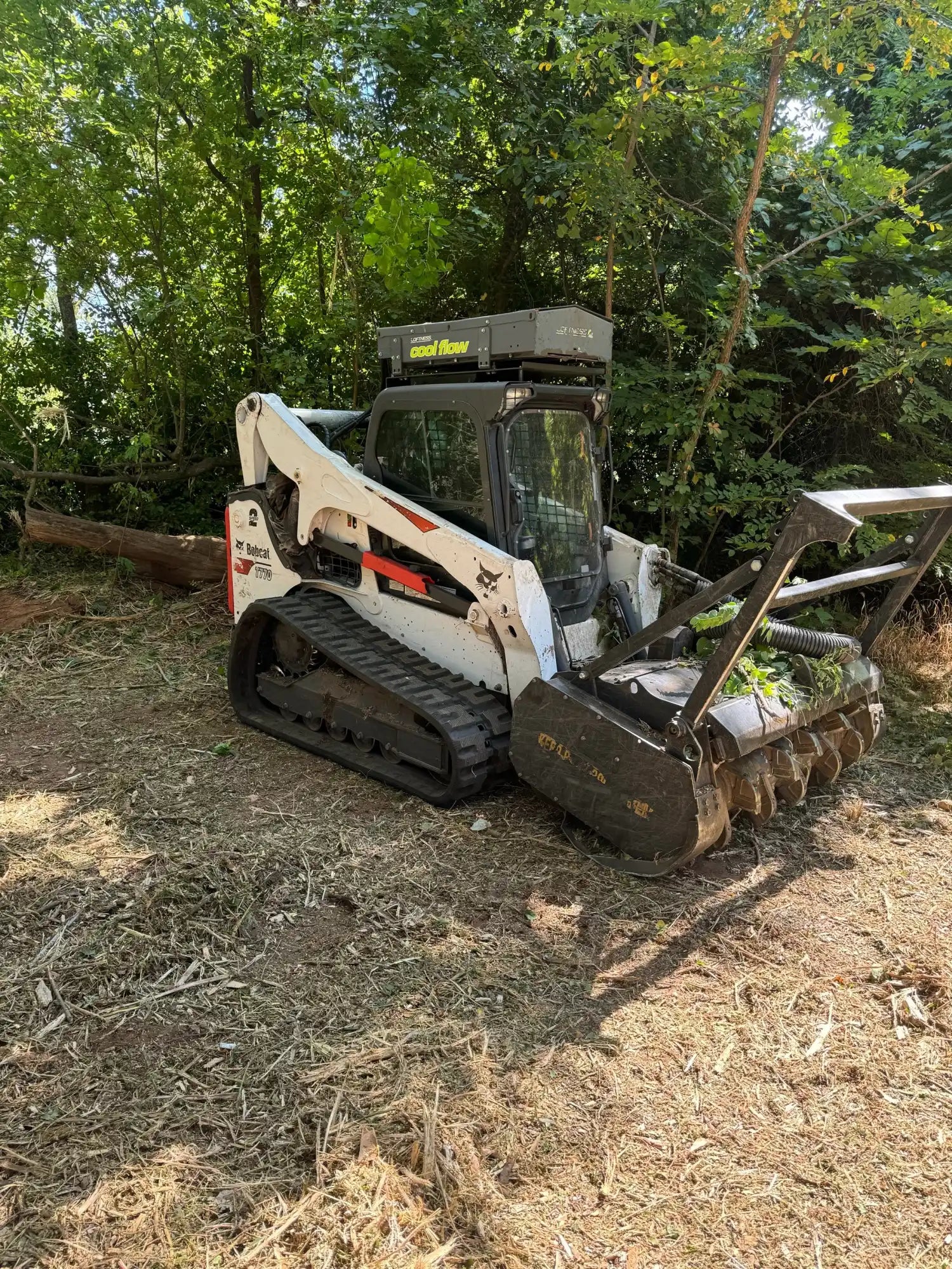 White compact track loader with a mulching attachment.