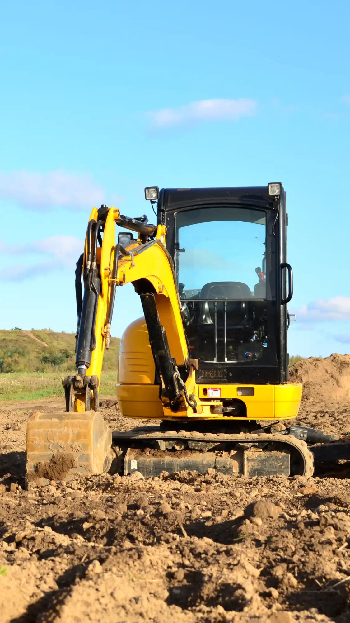 A yellow Caterpillar mini excavator on a worksite, representing the heavy equipment our support team can assist with.