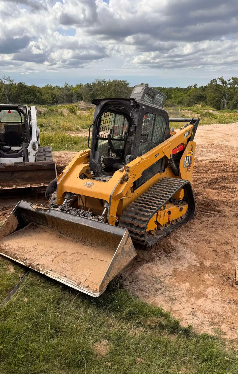 Yellow compact track loader with a front bucket.